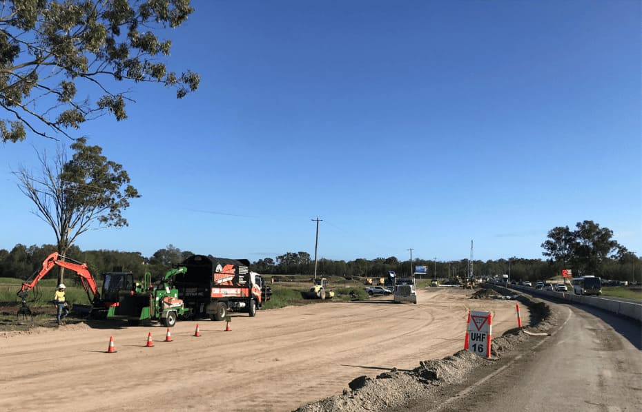 Professional commercial tree services crew performing large-scale tree removal using heavy machinery at a civil construction site.